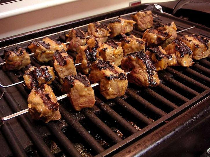 Grilling meat on an electric grill with charcoal
